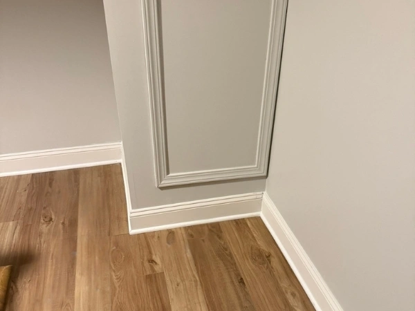 White baseboards installed around wall corners beside decorative molding