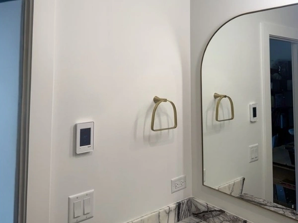 Painted bathroom walls around an arched mirror, stone backsplash, outlets, and towel ring