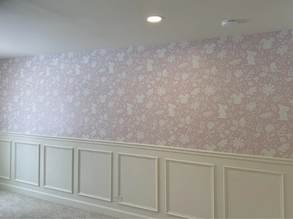 Finished room with pink patterned wallpaper, white chair rail, lower wall molding, and painted trim