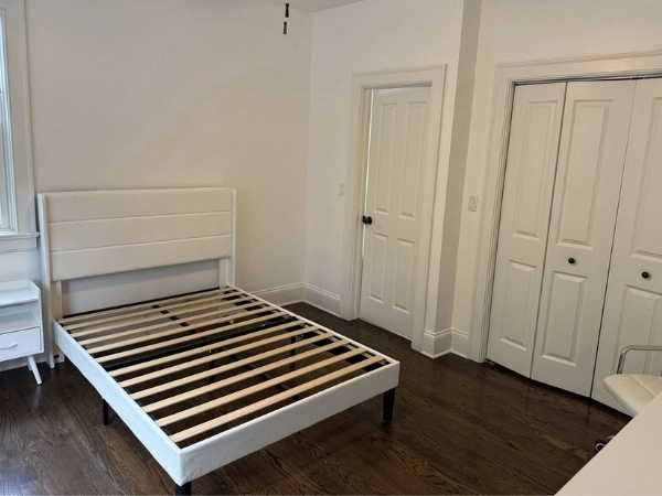 Finished bedroom with white walls, several interior doors, white trim, dark hardware, and wood flooring