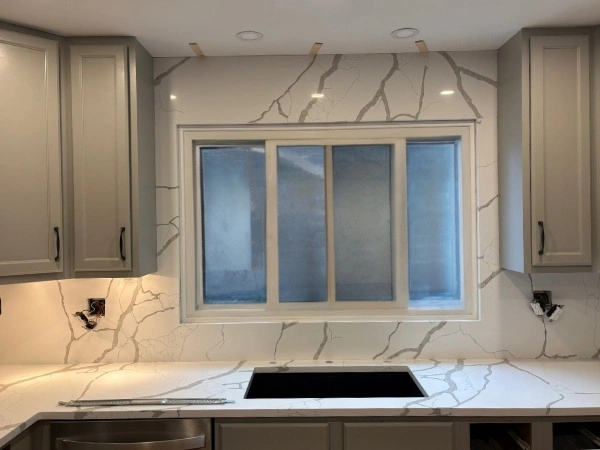 Kitchen with a quartz countertop and full-height slab backsplash around the window